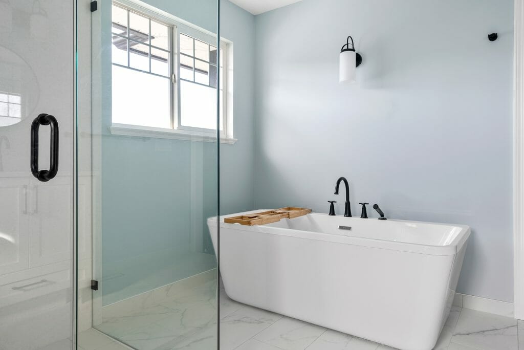 A view of a large white soaker bathroom tub taken from inside the bathroom walk-in shower.