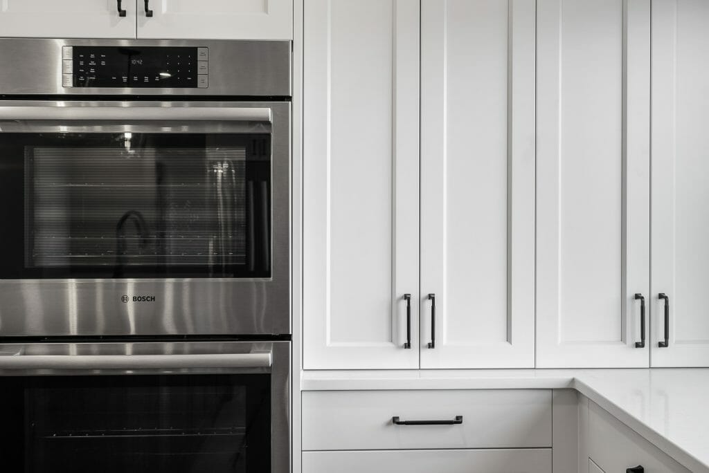 Renovated white kitchen with stainless steel built-in double oven.