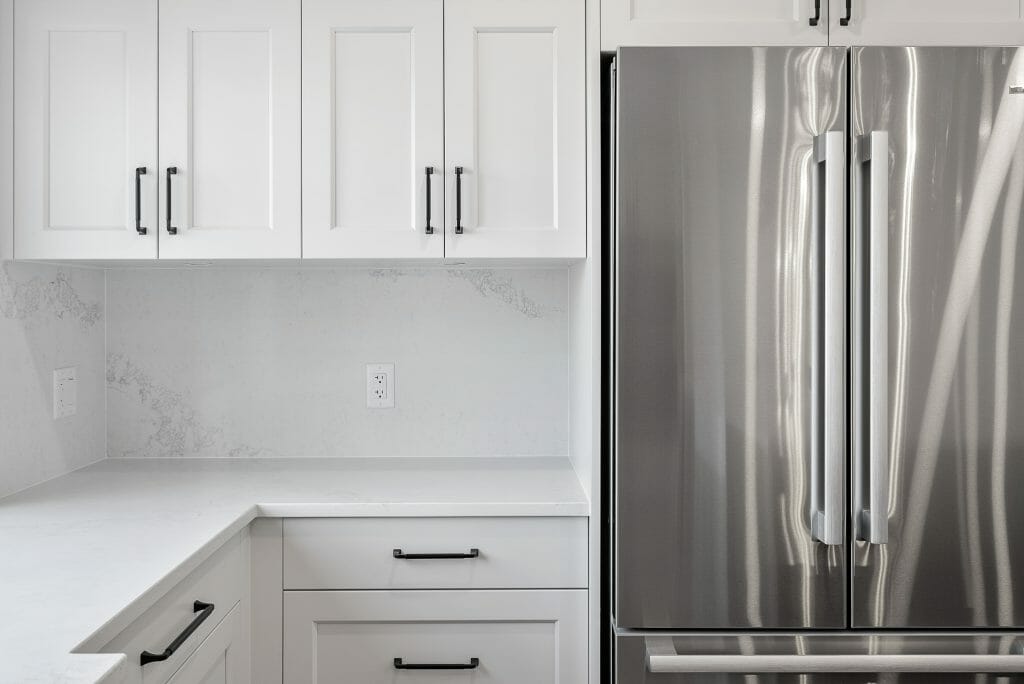 Renovated white kitchen with stainless steel double door fridge.