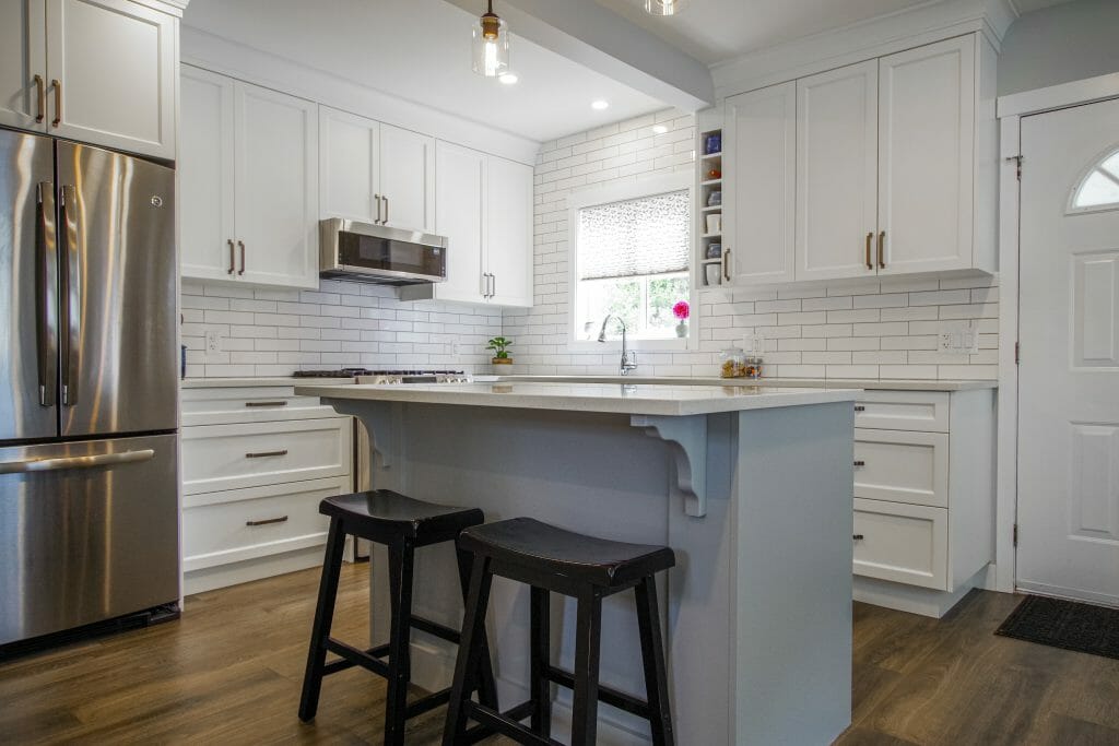 A kitchen renovation with white modern kitchen cabinets, an island, and stainless steel appliances.